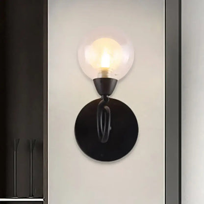 Black wall lamp with a clear glass globe and round black backplate, exposed bulb on Tampa Home & Garden Store