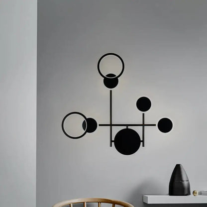 Black metallic wall sconce by Decorbites with geometric circle design and intersecting rods on Tampa Home & Garden Store
