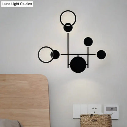 Black metallic wall sconce by Decorbites with circular rings and geometric arms on light wall on Tampa Home & Garden Store