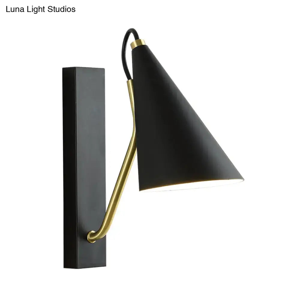 Black brass tapered wall sconce with curved gold arm and conical shade mounted on backplate on Tampa Home & Garden Store