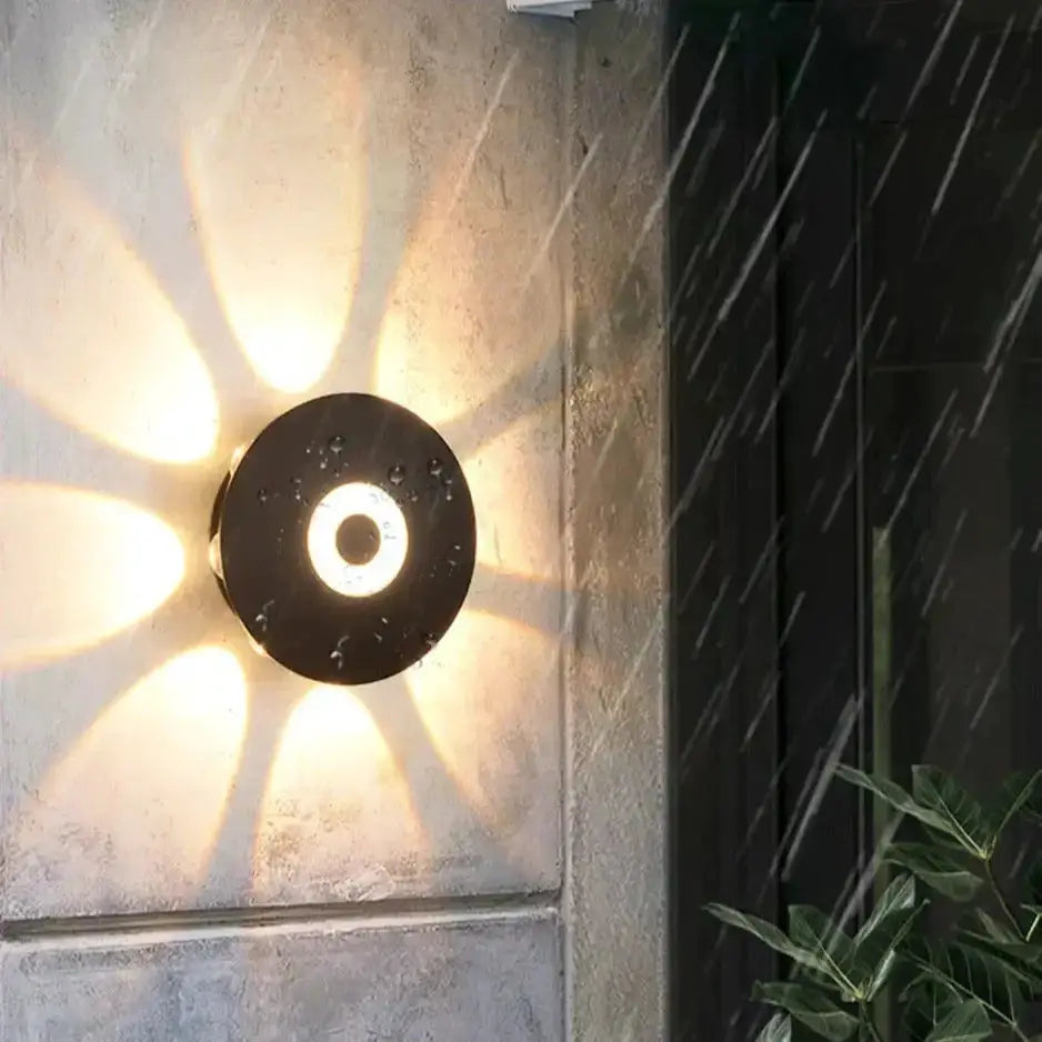 Modern black circular LED outdoor wall sconce by Decorbites on stone wall warm glow on Tampa Home & Garden Store
