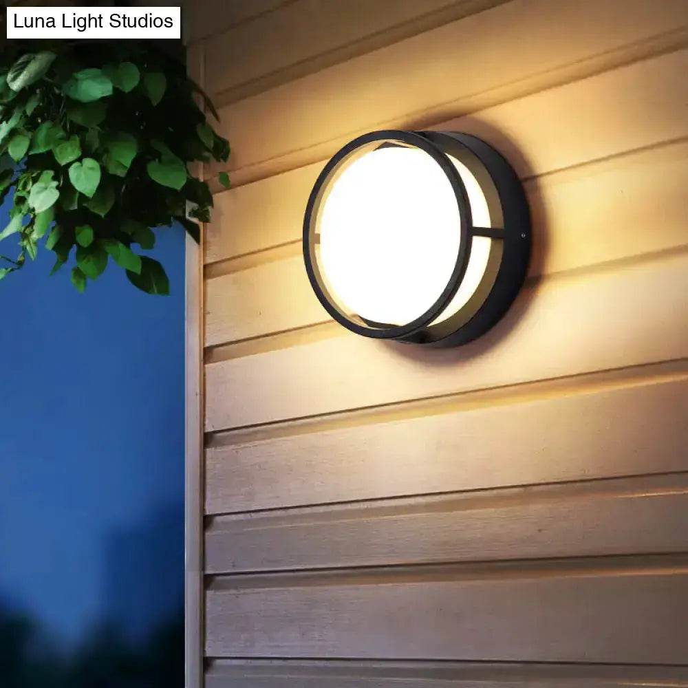 Decorbites black circular LED outdoor wall lamp with warm glow on beige siding on Tampa Home & Garden Store