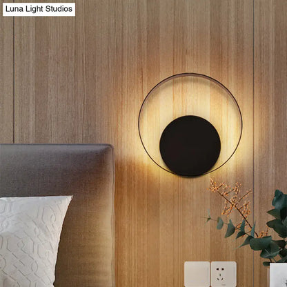Black circular LED wall sconce with black center and halo glow on wood wall by Decorbites on Tampa Home & Garden Store