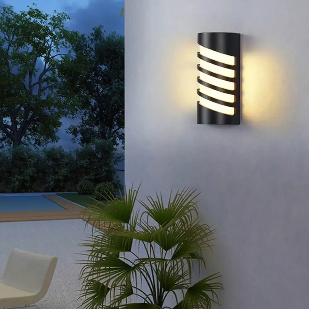Black curved patio sconce by Decorbites, outdoor wall light with slatted bands, warm glow on Tampa Home & Garden Store