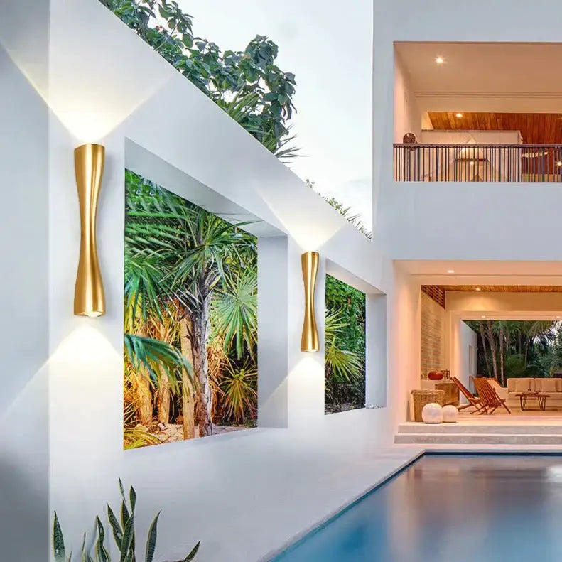 Decorbites brass curved IP65 outdoor wall sconce pair on white exterior wall beside pool on Tampa Home & Garden Store
