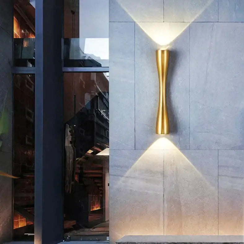 Decorbites gold curved IP65 outdoor wall sconce on gray stone wall uplight and downlight on Tampa Home & Garden Store