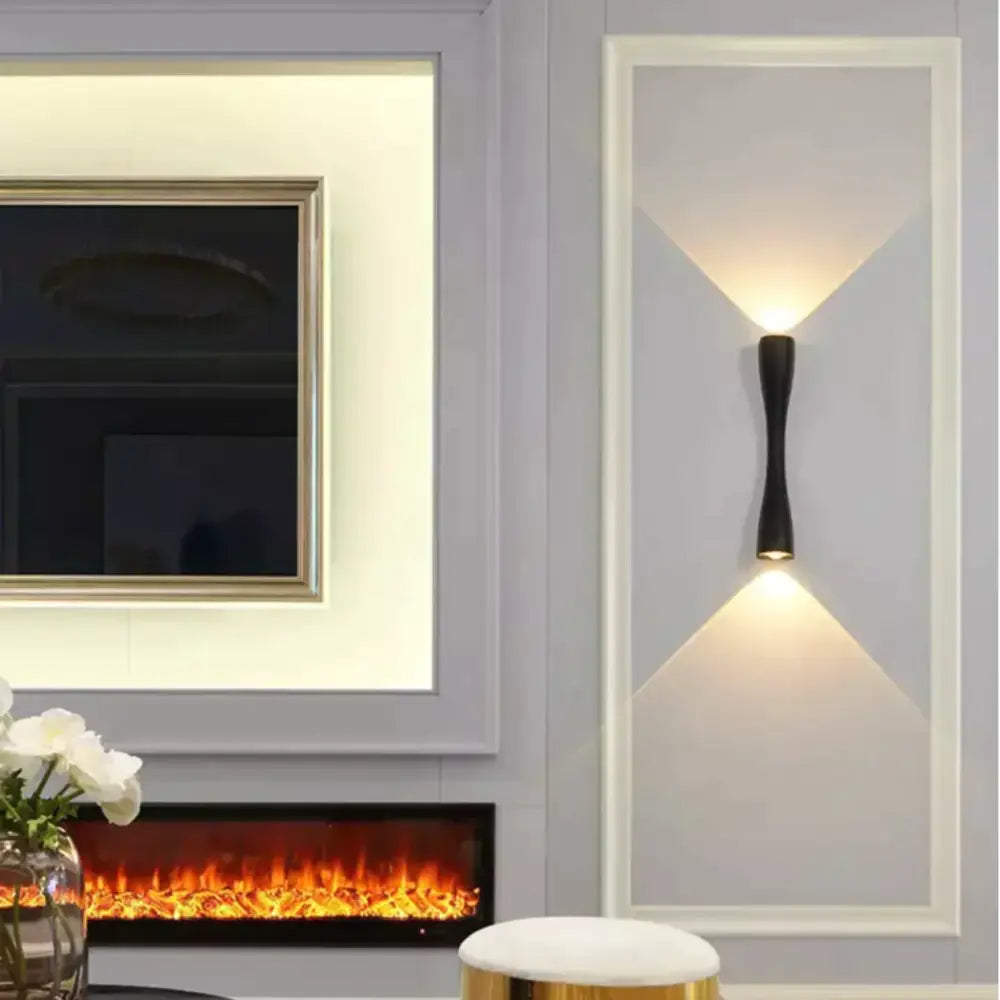 Black curved IP65 outdoor wall sconce on a light gray wall panel, dual up/down warm light on Tampa Home & Garden Store