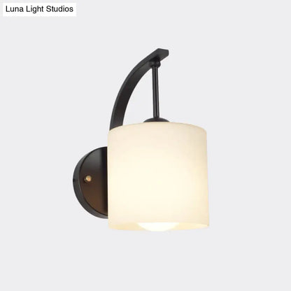 Black cylindrical opal glass wall sconce with curved metal arm on Tampa Home & Garden Store
