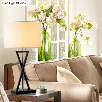 Black drum lamp with beige shade on a side table beside a sofa, green vases with white flowers on Tampa Home & Garden Store