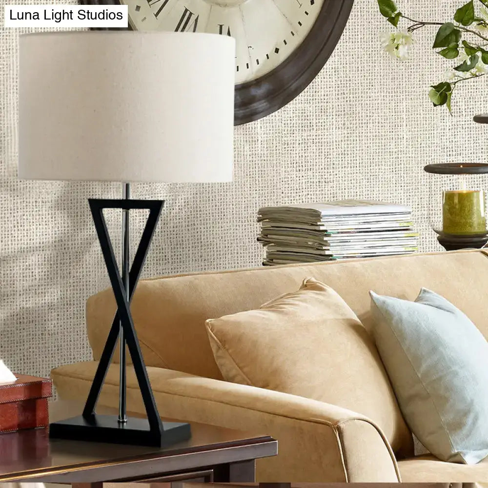 Black nightstand drum lamp with white fabric shade and black metal tripod base on a wood table on Tampa Home & Garden Store