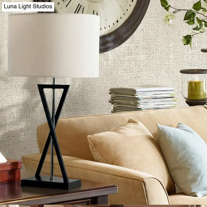 Black nightstand drum lamp with white fabric shade and black metal tripod base on a wood table on Tampa Home & Garden Store