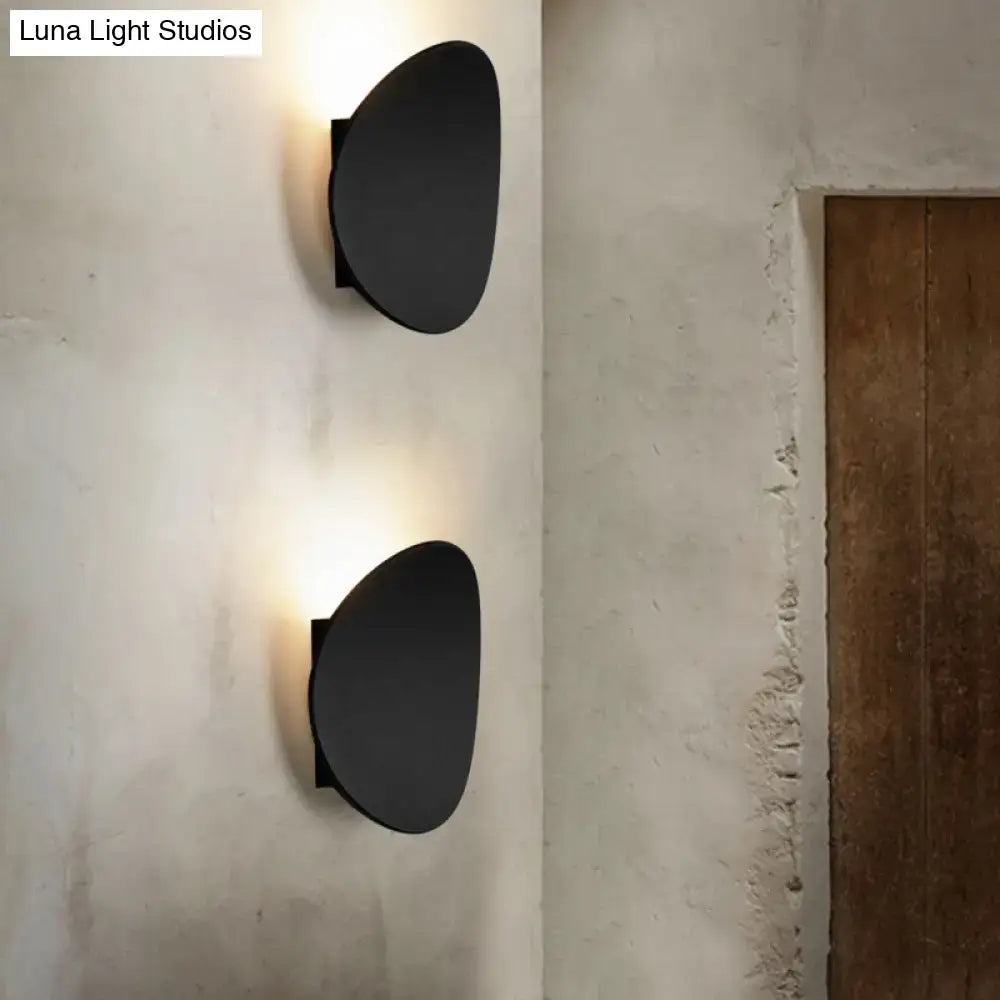 Black geometric wall sconce with two matte round discs emitting warm light on Tampa Home & Garden Store