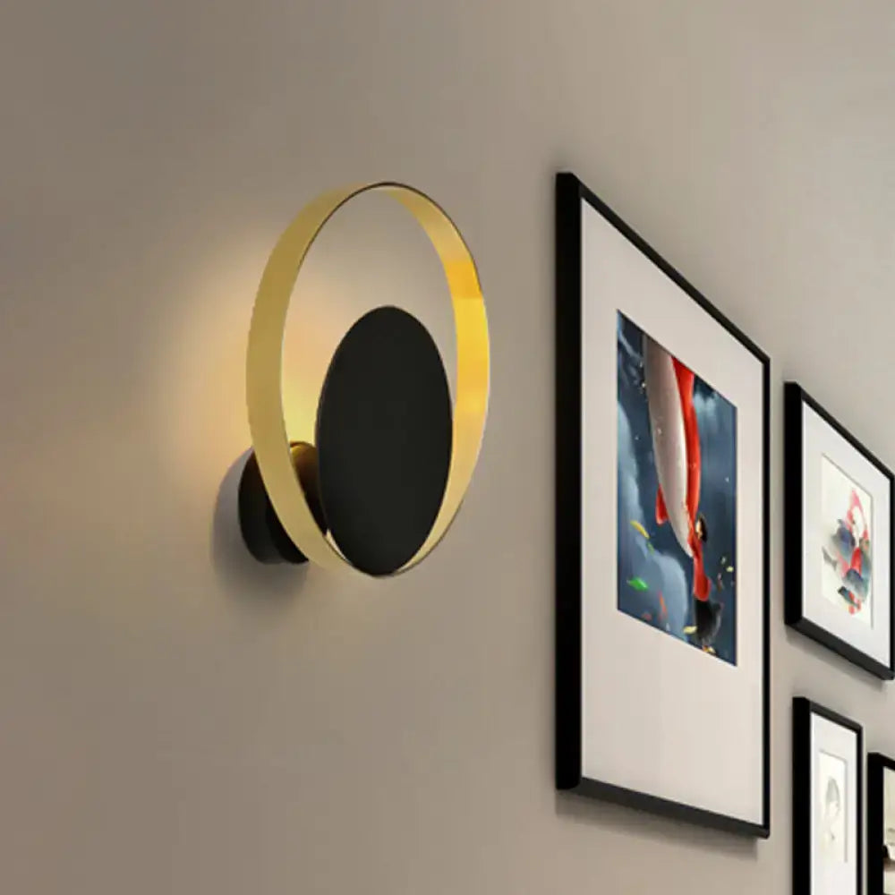 Black brass circular wall sconce with a gold ring and warm glow on Tampa Home & Garden Store