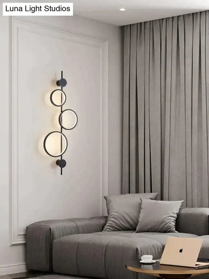 Black long wall sconce with four illuminated circular rings on a vertical bar by Decorbites on Tampa Home & Garden Store