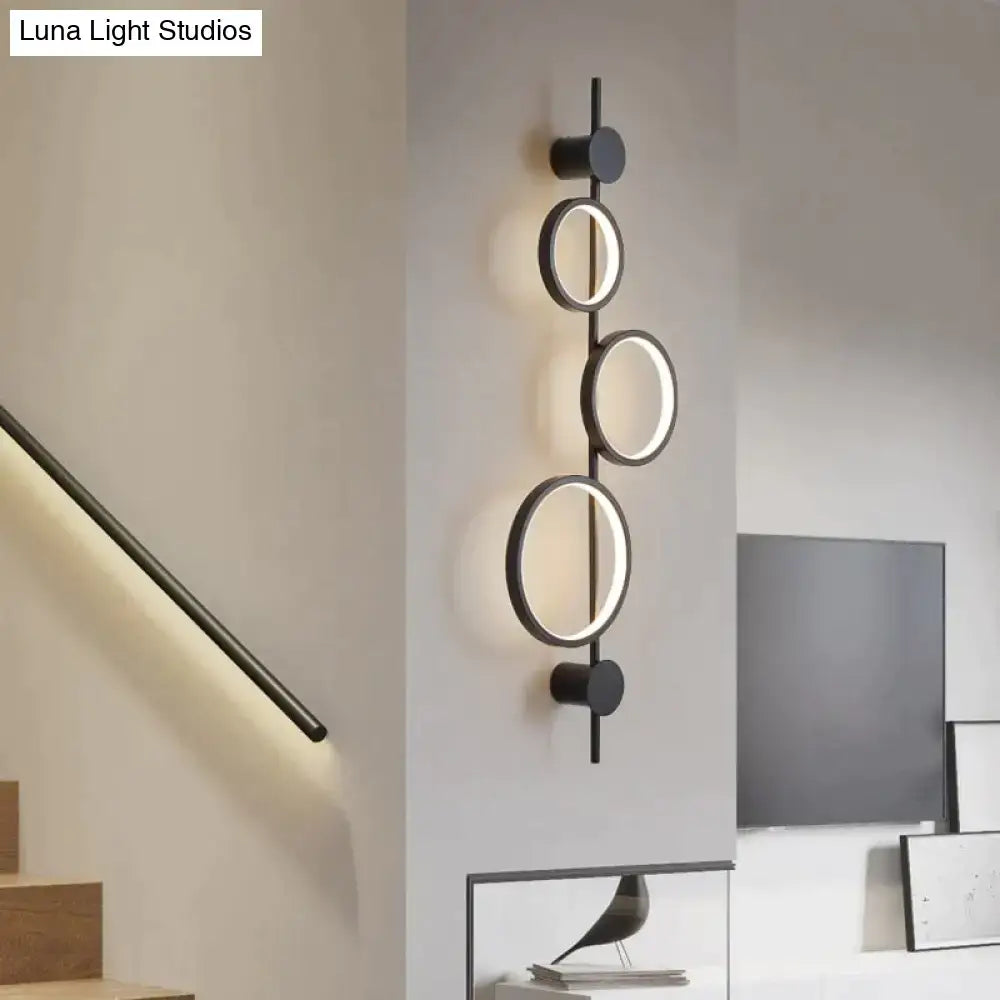 Black long wall sconce by Decorbites with three circular rings on a vertical metal bar on Tampa Home & Garden Store