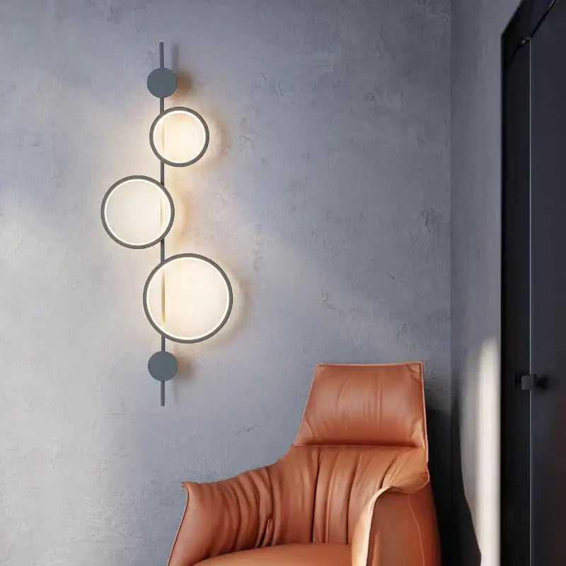 Black long wall sconce by Decorbites with three illuminated circular rings on a vertical bar on Tampa Home & Garden Store