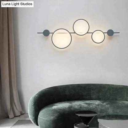 Black long wall sconce with three illuminated circular rings on a horizontal bar by Decorbites on Tampa Home & Garden Store