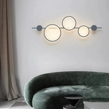 Black long wall sconce with three illuminated circular rings on a metal bar by Decorbites on Tampa Home & Garden Store