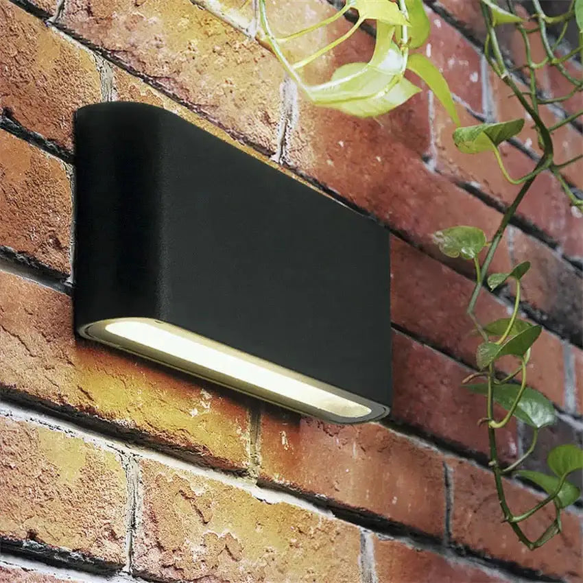 Black outdoor wall light by Decorbites, metal fixture with downward glow on brick wall on Tampa Home & Garden Store