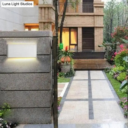 Black outdoor wall light fixture with rectangular frosted panel on gray stone wall on Tampa Home & Garden Store
