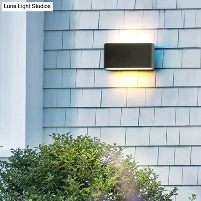 Decorbites black outdoor wall light sconce with warm downward glow on blue-gray shingle siding on Tampa Home & Garden Store