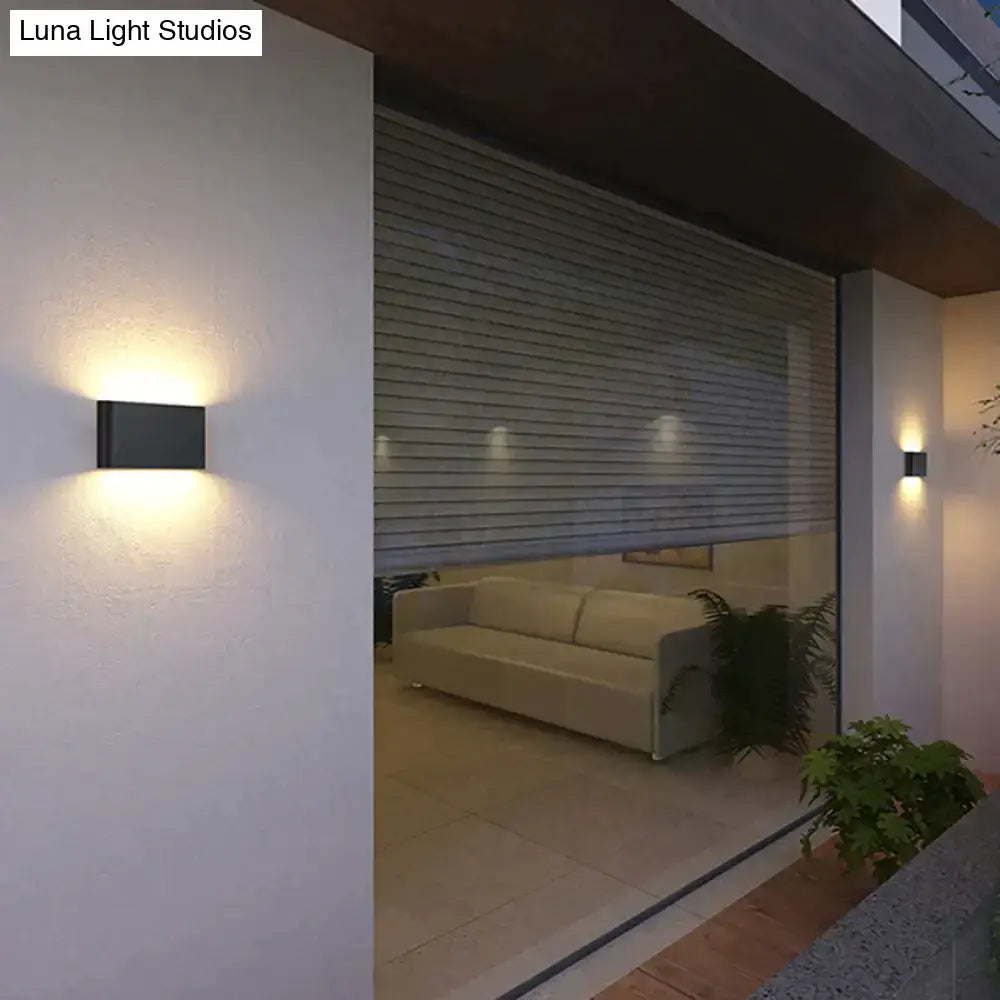 Black Decorbites outdoor wall light sconce, rectangular metal fixture, emits warm glow on Tampa Home & Garden Store