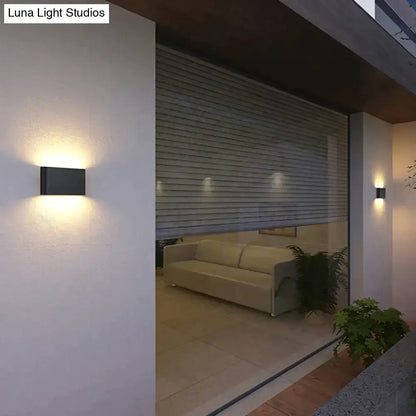 Black Decorbites outdoor wall light sconce, rectangular metal fixture, emits warm glow on Tampa Home & Garden Store