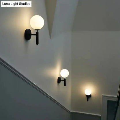 Black glass globe wall sconces, set of three with matte black mounts along stair wall on Tampa Home & Garden Store