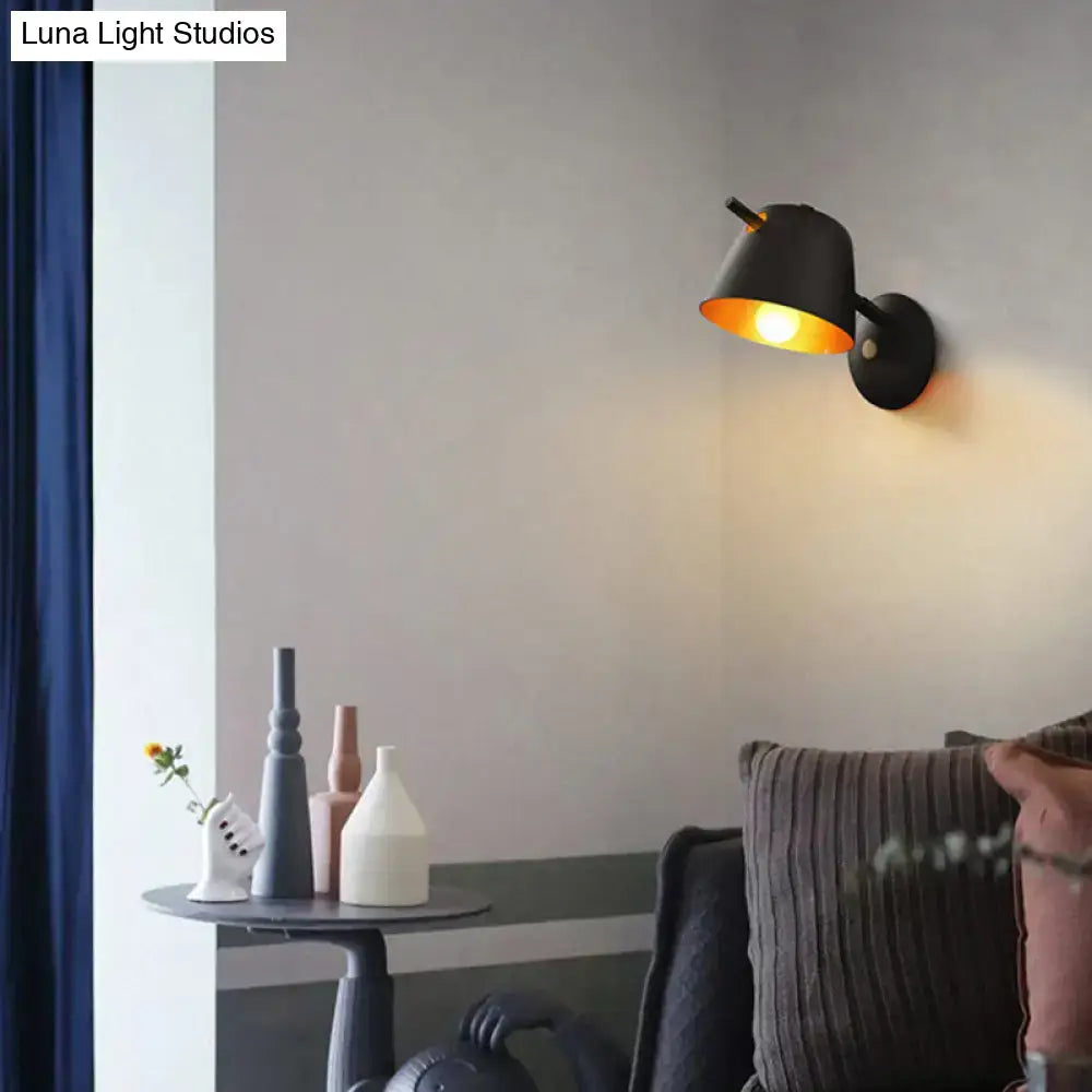 Black metal wall light with downward cone shade casting warm glow above the sofa on Tampa Home & Garden Store