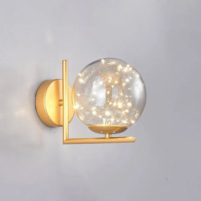 Globe wall sconce with clear glass sphere and warm string lights, gold brass finish on Tampa Home & Garden Store