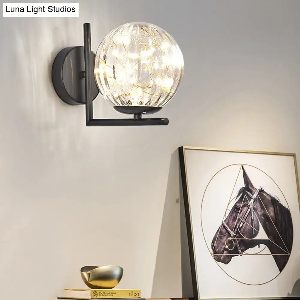 Black globe wall sconce with crackle glass orb and matte metal arm, warm LED glow on Tampa Home & Garden Store