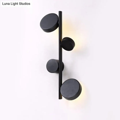 Black circle wall sconce with four matte black discs on a vertical bar, warm LED glow on Tampa Home & Garden Store