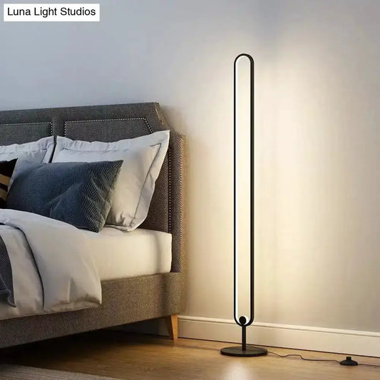 Decorbites modern black oval floor lamp with warm white light beside a bed in a bedroom on Tampa Home & Garden Store