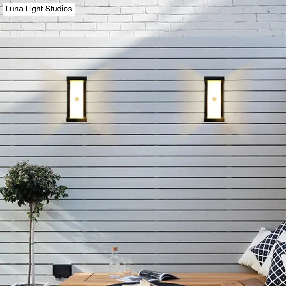 Black outdoor LED wall sconces (2) with frames on white siding, casting warm light on Tampa Home & Garden Store