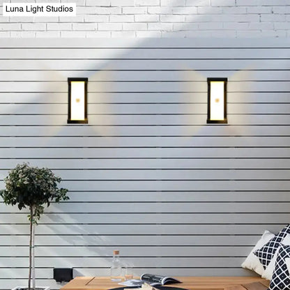 Black outdoor LED wall sconces (2) with frames on white siding, casting warm light on Tampa Home & Garden Store
