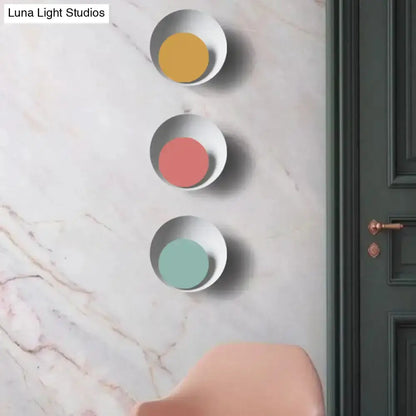 Three white round sconces with pastel centers yellow pink mint on marble wall beside door on Tampa Home & Garden Store