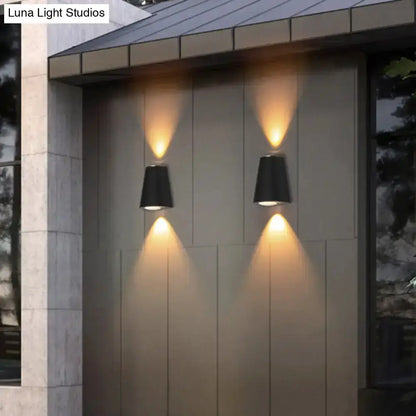 Two black trapezoid wall lights by Decorbites, casting warm uplight and downlight on wall on Tampa Home & Garden Store