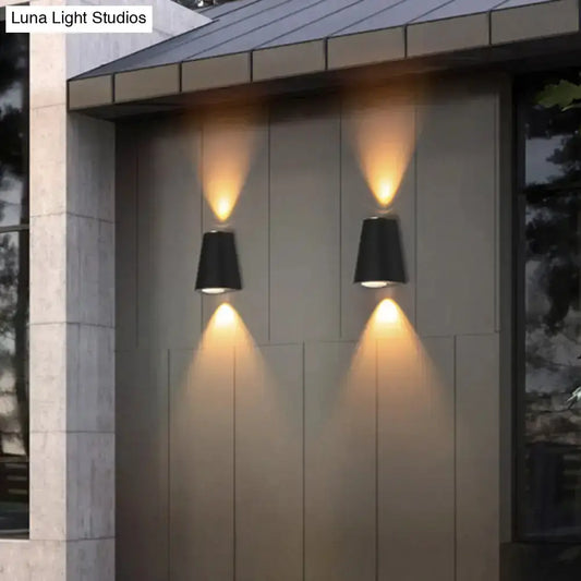 Two black trapezoid wall lights by Decorbites, casting warm uplight and downlight on wall on Tampa Home & Garden Store