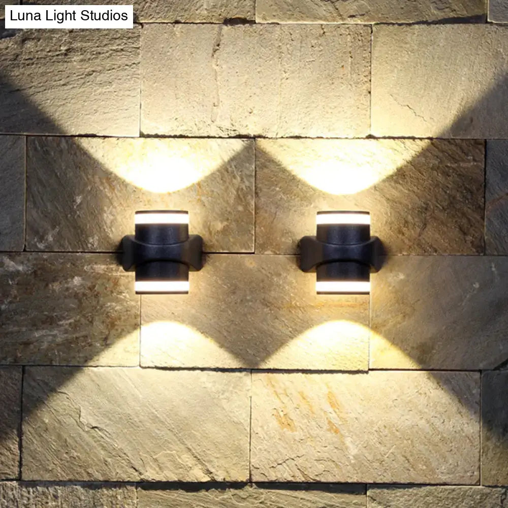 Black tubular wall sconces pair on a stone wall, casting warm light patterns on the surface on Tampa Home & Garden Store