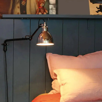 Articulated black metal bedroom wall lamp with a copper shade, mounted over a blue headboard on Tampa Home & Garden Store