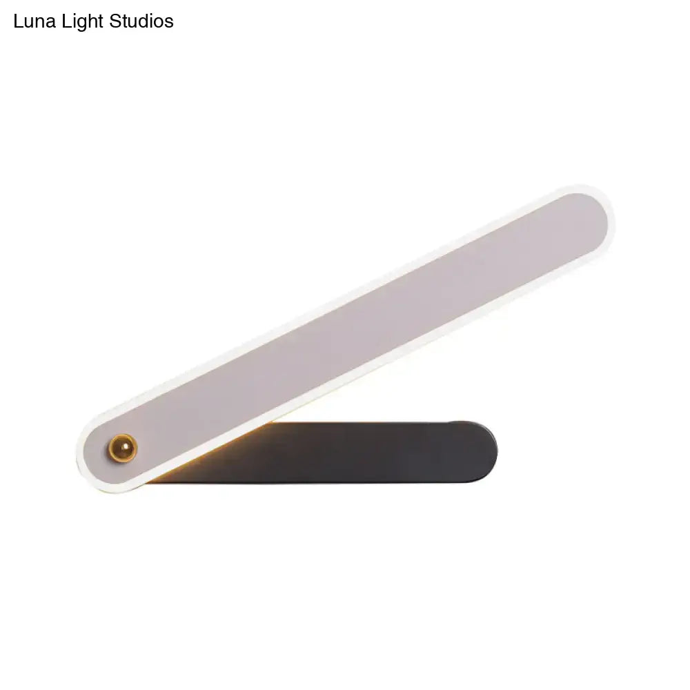 Decorbites black metal LED sconce with slim dual-arm design emitting warm light on Tampa Home & Garden Store