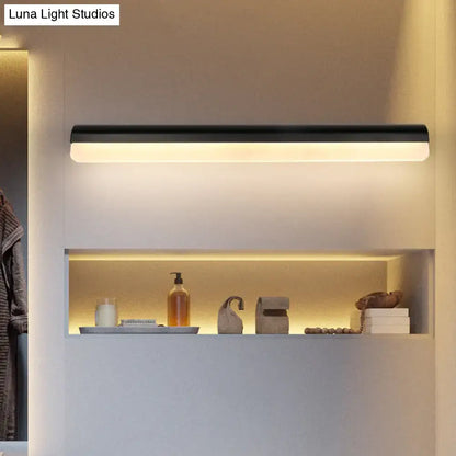 Modern black and white linear LED bathroom wall sconce above warm shelf lighting on Tampa Home & Garden Store