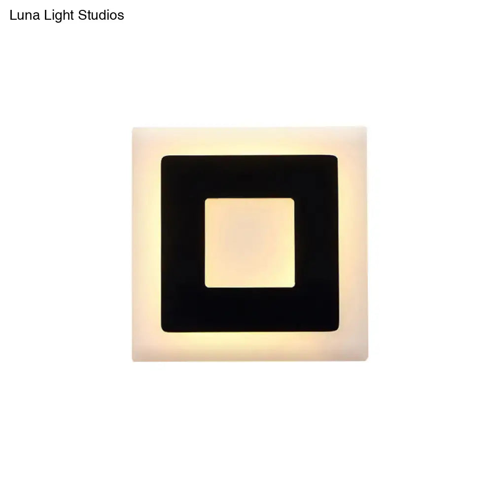 Acrylic square wall sconce with a bold black inner square frame and warm backlit glow on Tampa Home & Garden Store