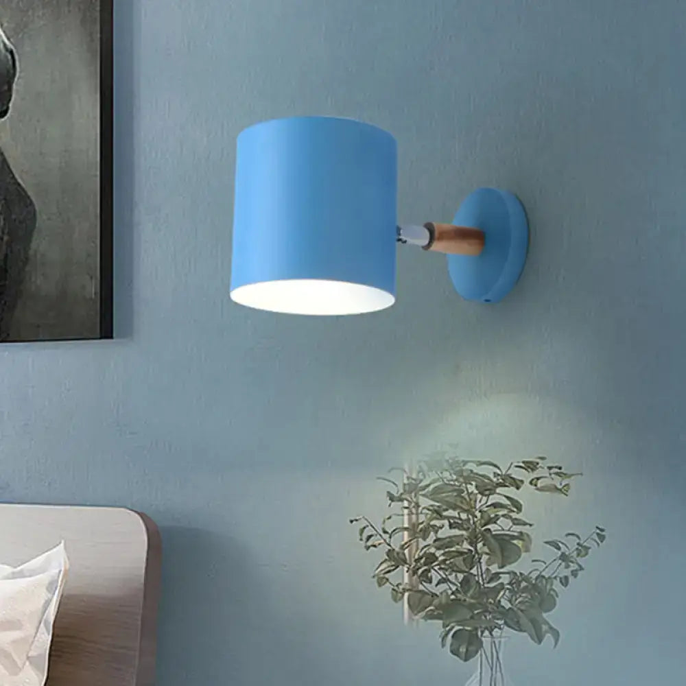 Blue tubular wall sconce by Decorbites with blue drum shade and wood arm on blue wall on Tampa Home & Garden Store