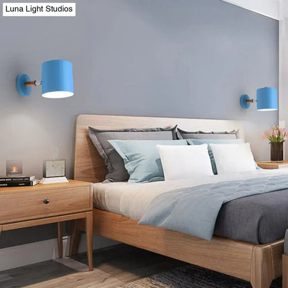 Blue tubular wall sconces pair with brass arms mounted on blue-gray wall above a wooden bed on Tampa Home & Garden Store