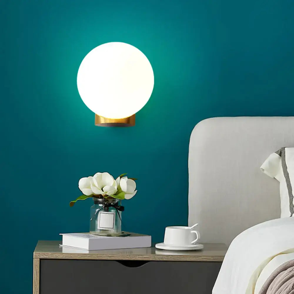 Brass Opal Wall Sconce with round white opal globe and brass wall mount on teal bedroom wall on Tampa Home & Garden Store