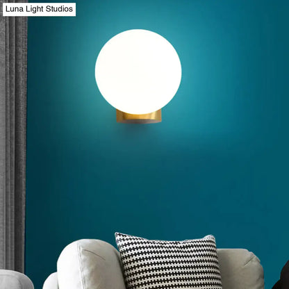 Brass Opal Wall Sconce with white globe and brass mount on teal wall by Decorbites on Tampa Home & Garden Store
