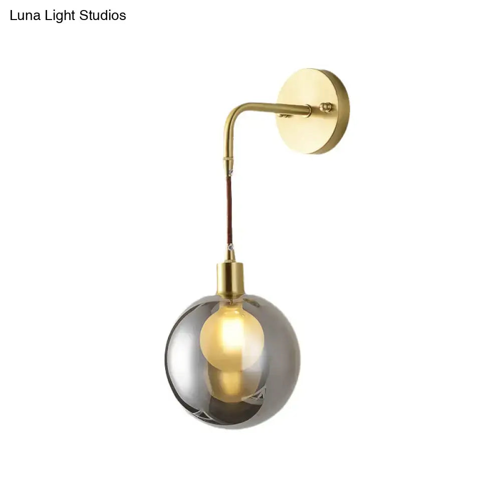 Brass smoke glass sconce by Decorbites; curved arm, smoky globe on Tampa Home & Garden Store