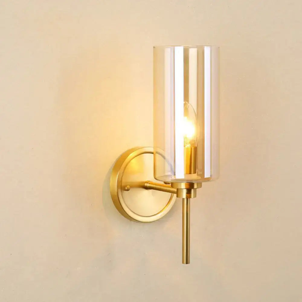 Decorbites brass smoked glass single-light wall sconce with cylindrical shade and warm glow on Tampa Home & Garden Store