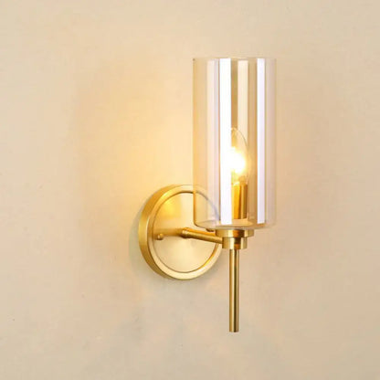 Decorbites brass smoked glass single-light wall sconce with cylindrical shade and warm glow on Tampa Home & Garden Store